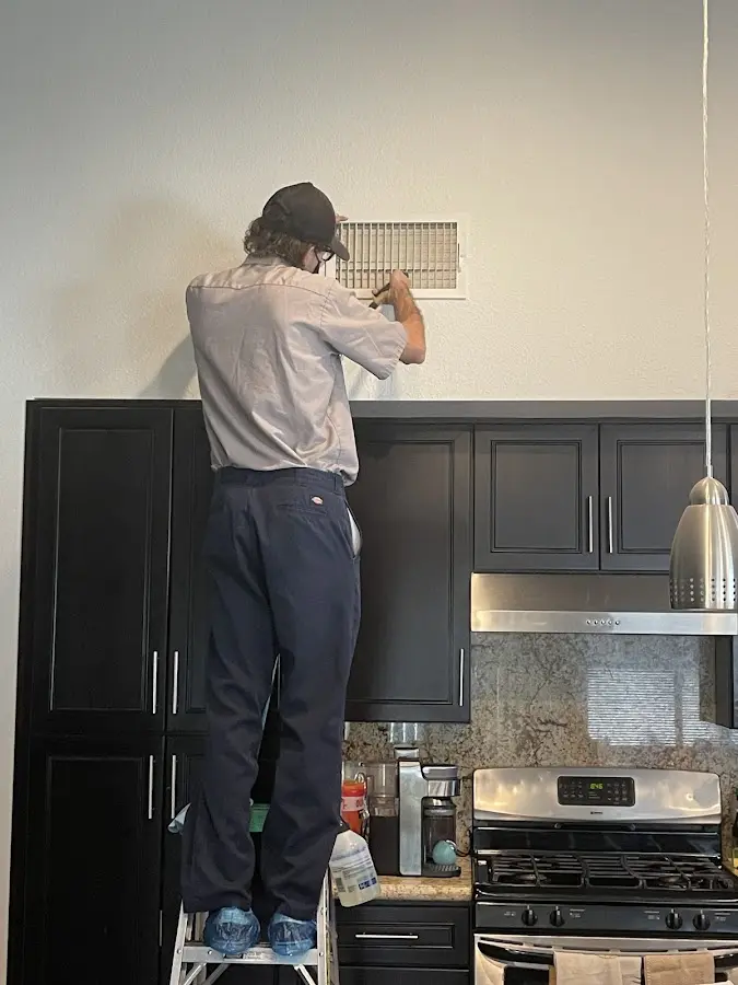 Technician inspecting an air vent during HVAC service in Dalhart